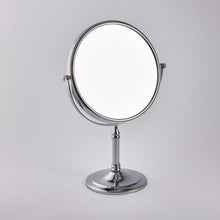 Load image into Gallery viewer, A silver-colored freestanding two-sided vanity mirror with a brass base and stainless steel accents, on a white background.