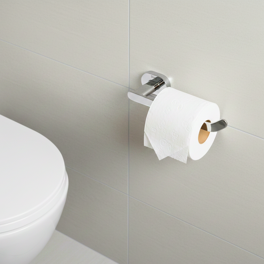 Toilet paper roll on a holder next to a toilet in a bathroom.