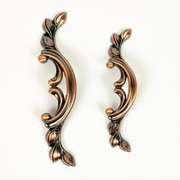 A pair of red oxide zinc alloy cabinet pulls with leaf-like designs.