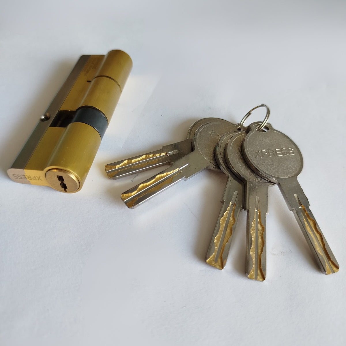 Gold lock cylinder and keys on a white background
