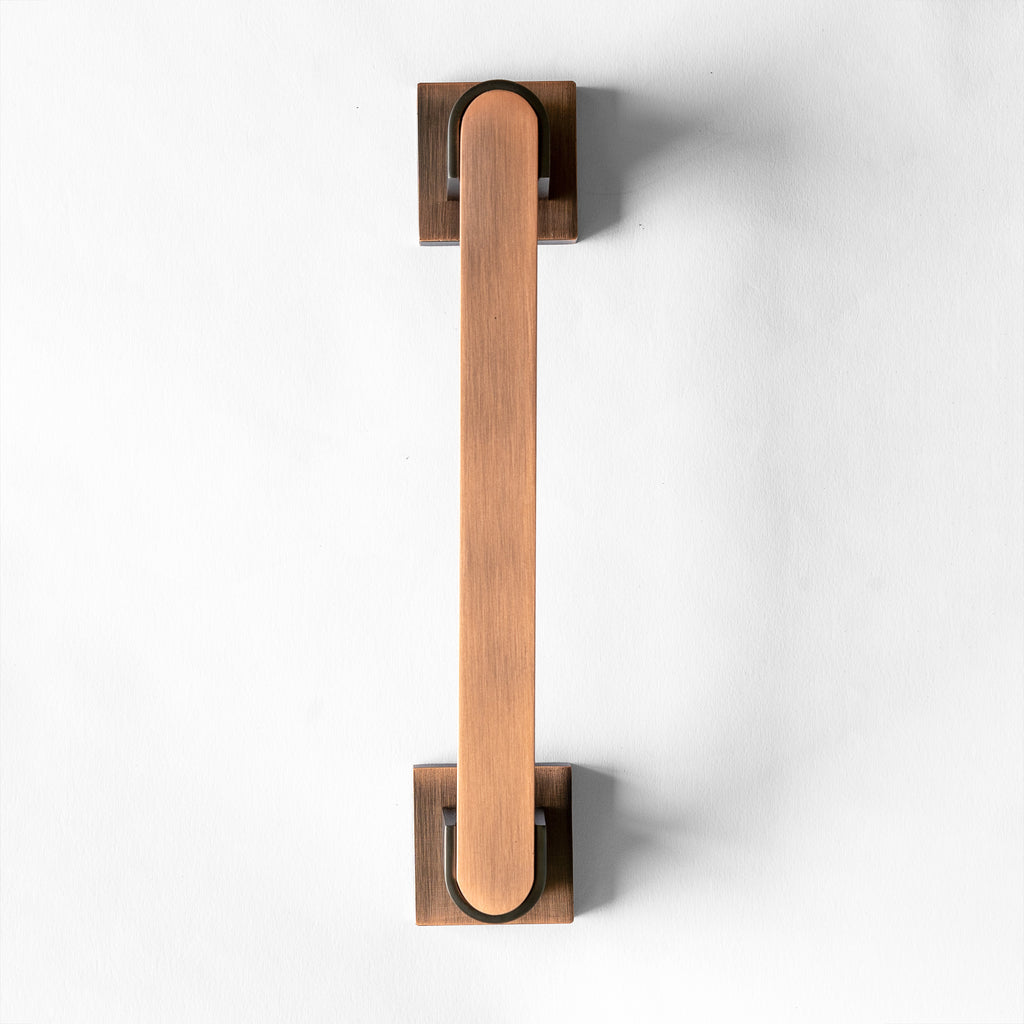 A Red Oxide metal door pull handle against a white background.