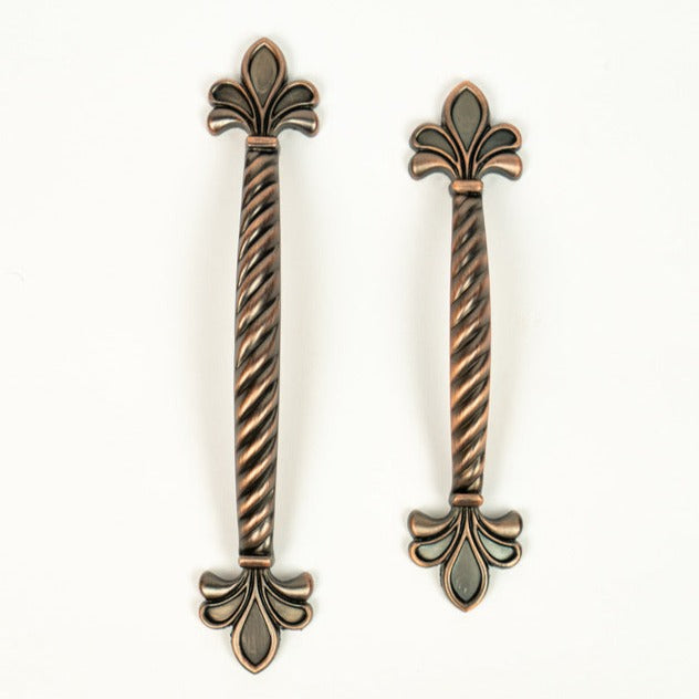 A pair of red bronze cabinet pulls with a leaf pattern on a white background.