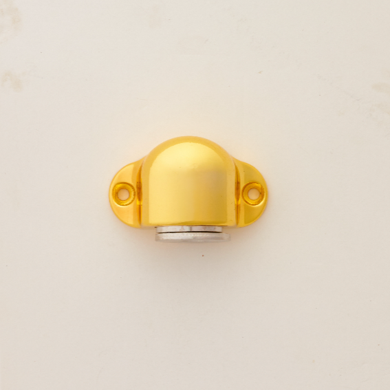A gold-colored magnetic door stopper mounted on a white door.