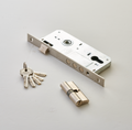 A silver computer door lock with a set of keys and a cylindrical lock component placed on a white surface.
