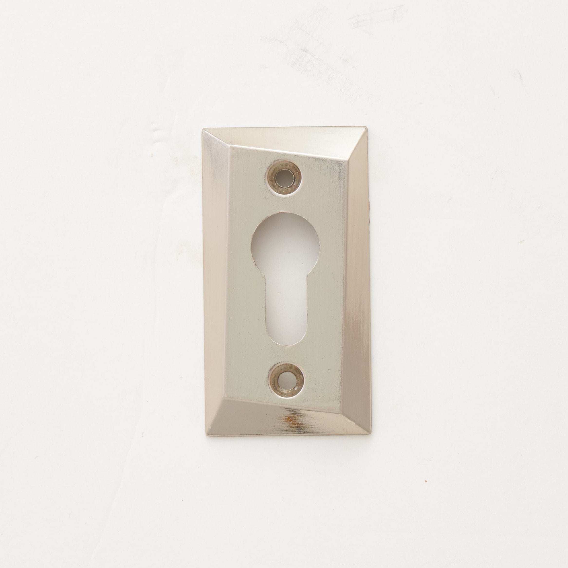 A silver door cylinder cover with a keyhole, against a white background