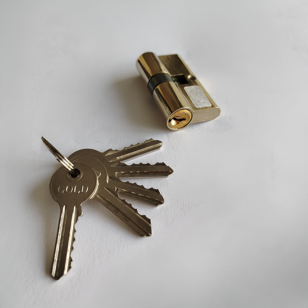 Gold cylindrical lock and keys on a white background