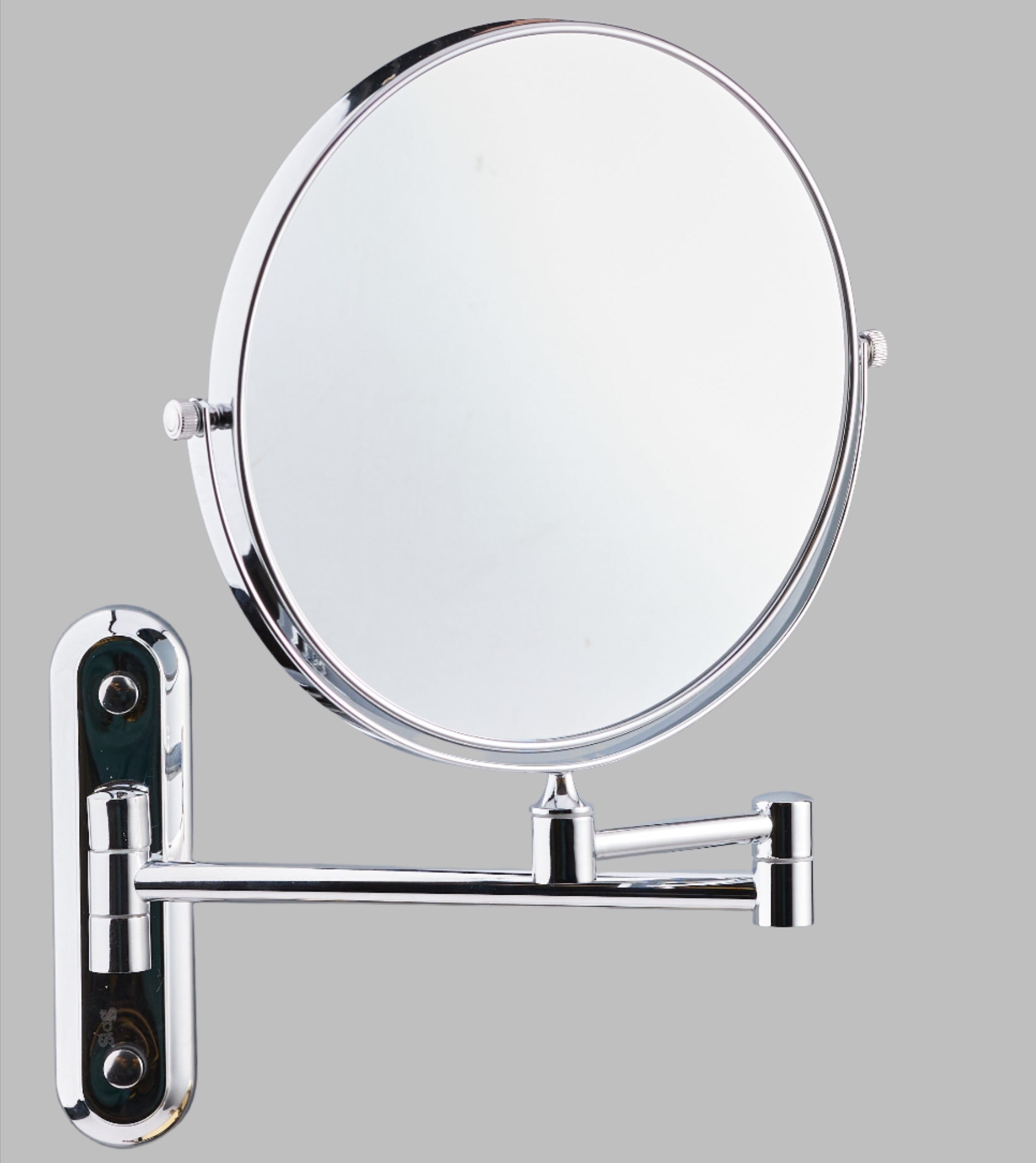 A silver extendable magnifying wall mirror with a brass*stainless steel construction, mounted on a wall arm.