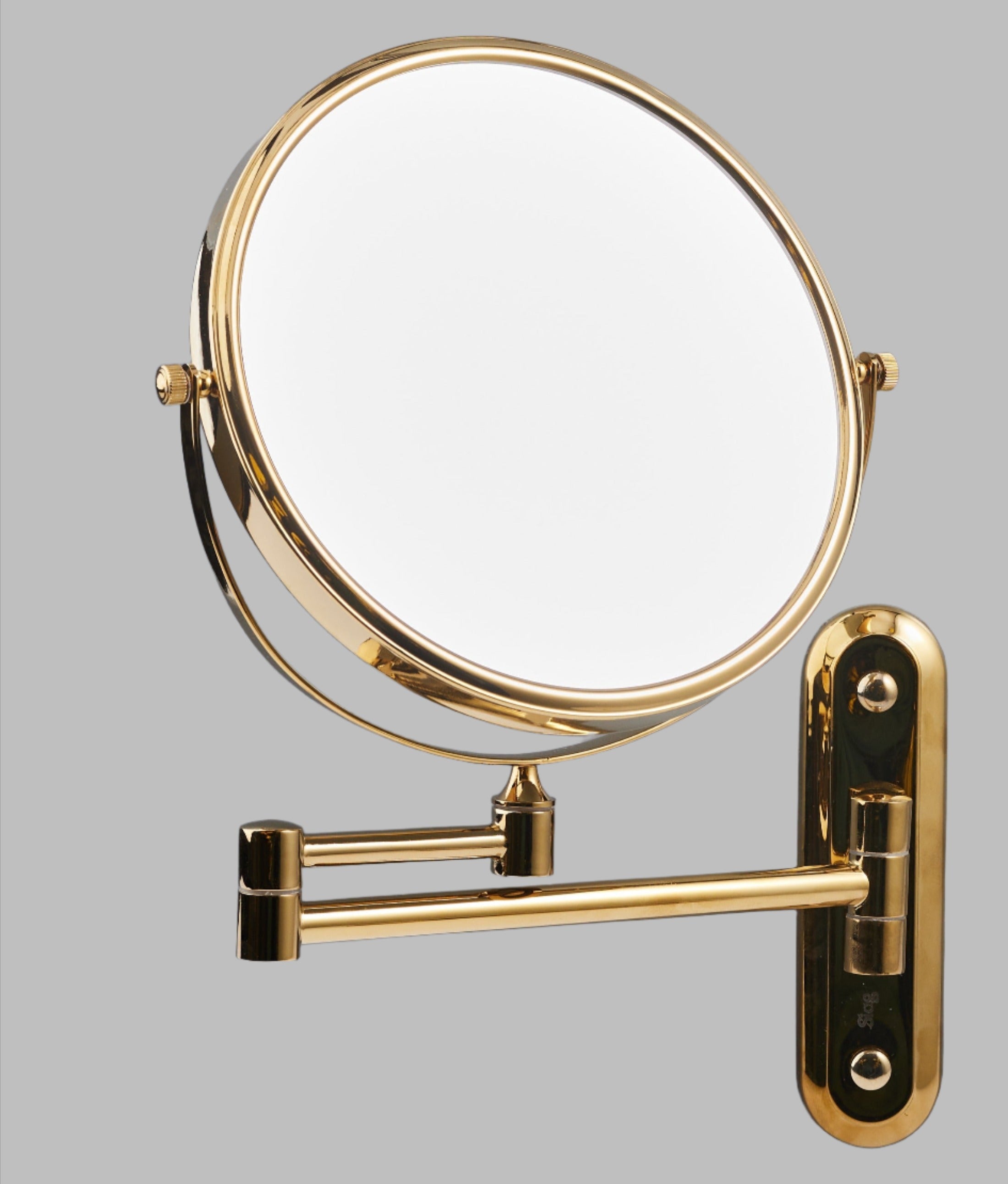 A gold-colored extendable magnifying wall mirror with a brass and stainless steel construction, mounted on a wall bracket.